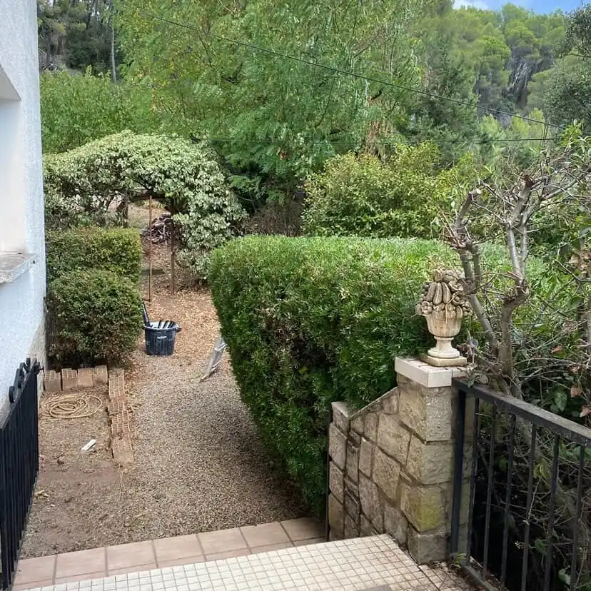 Haie de laurier taillée au cordeau le long d'une allée de gravier, pilier de pierre et portail aux Arcs-sur-Argens